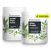 Zwei Beutel Nahrungsergänzungsmittel der Marke NATURAL ELEMENTS im grünen Blätter-Design: einer mit der Aufschrift „Kreatin Monohydrat“ und der andere mit „Whey Protein Vanillegeschmack“, Teil des Kraftsport Basic Bundle.